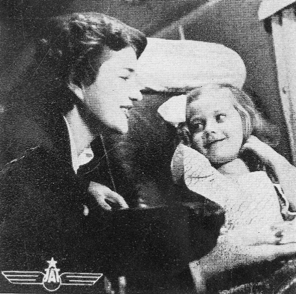 Figure 5.2. A smiling stewardess crouches next to the plane seat of a young girl, who smiles back at her.