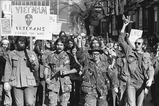 Figure 44. Vietnam veterans in camouflage and parts of old uniforms marching with toy rifles and a sign that says “Vietnam Veterans Against the War.”