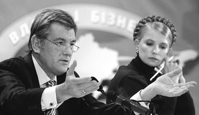 Ukrainian president Viktor Yushchenko and Prime Minister Yulia Tymoshenko sitting in front of microphones at a speaker’s platform. Yushchenko is gesturing with his hands.