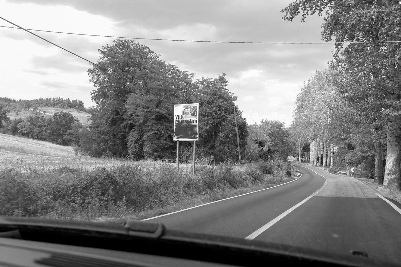 Figure 4.3. A view from a car windshield of a road with a sign advertising the Villa. Most of the sign has been graffitied over in black.