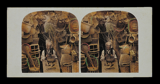 Figure I.3. An old man, balding with white hair, weaves a basket on a worktable. Hanging wicker baskets and chairs form an arch around him.