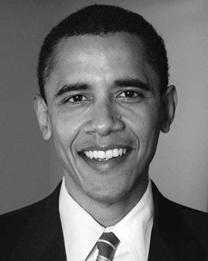 A headshot of a man with closely cropped dark hair. He is wearing a suit and tie and smiling.