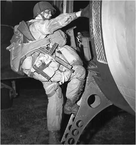 Figure 2. A soldier heavily loaded with gear climbs up steps to a transport aircraft at night.