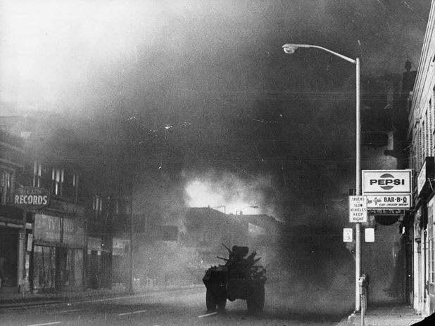 Figure 10. A lone tank rumbles down a deserted street, smoke billowing in the air, obscuring most of the sunlight, as the tank approaches a lone light post and a Pepsi sign on the side of a barbecue joint.