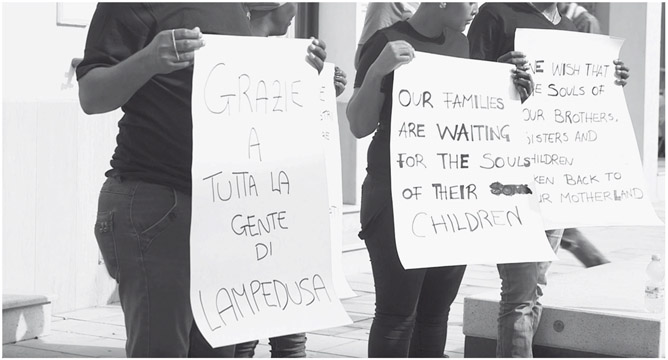 Figure 15. Three people hold large sheets of paper in front of them saying: “Grazie a tutta la gente di Lampedusa,” “Our families are waiting for the souls of their children,” “We wish that the souls of our brothers, sisters and children taken back to our motherland.”