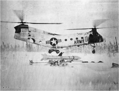 Figure 5. A rocket is being attached to a helicopter hovering just above in a snow-covered field.