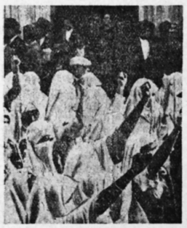 Figure 2.3. A black-and-white photograph of Muslim women dressed in white haiks among a crowd of protestors holding up fists