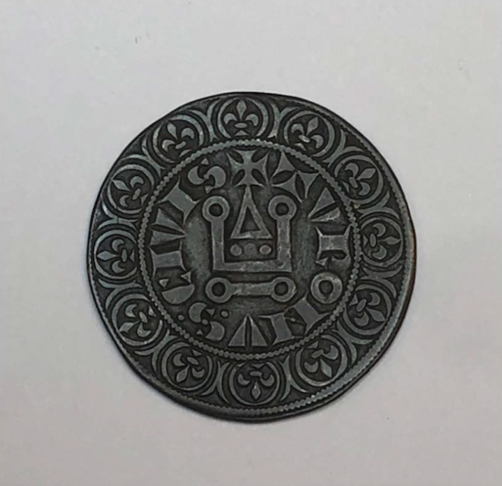 Figure 8.2. The reverse of a silver coin with a cross in the middle and two concentric rings of text around the edge.