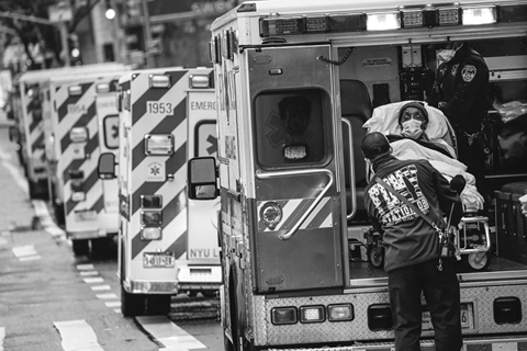Figure 4. Two emergency medical workers remove a patient from one of a long line of ambulances.