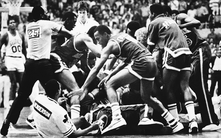 A single referee attempts to restore order amid a third-period fight on the court. A core of at least ten players—and Knicks coach Hubie Brown—cluster around Danny Ainge and Darrell Walker, as Celtics center Robert Parish looks on from a distance.