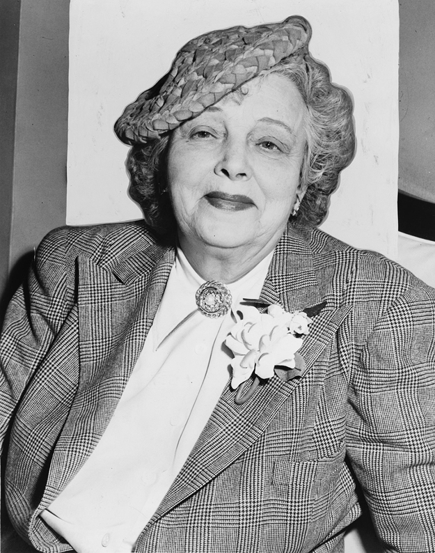 Figure 16. An older Anderson smiles and faces pleasantly toward the viewer. She wears a flat, woven hat, tilted left and a tailored jacket with a flower on her lapel. Her blouse is closed at the collar with an intricate brooch.