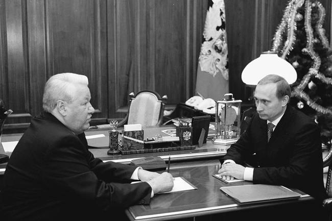 Boris Yeltsin and Vladimir Putin, looking serious, sitting across from one another at Yeltsin’s desk, December 31, 1999.