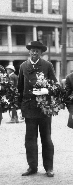 Wearing white gloves and his uniform jacket, Josiah Hasbrook bears a wreath to the cemetery on the holiday that honored soldiers.