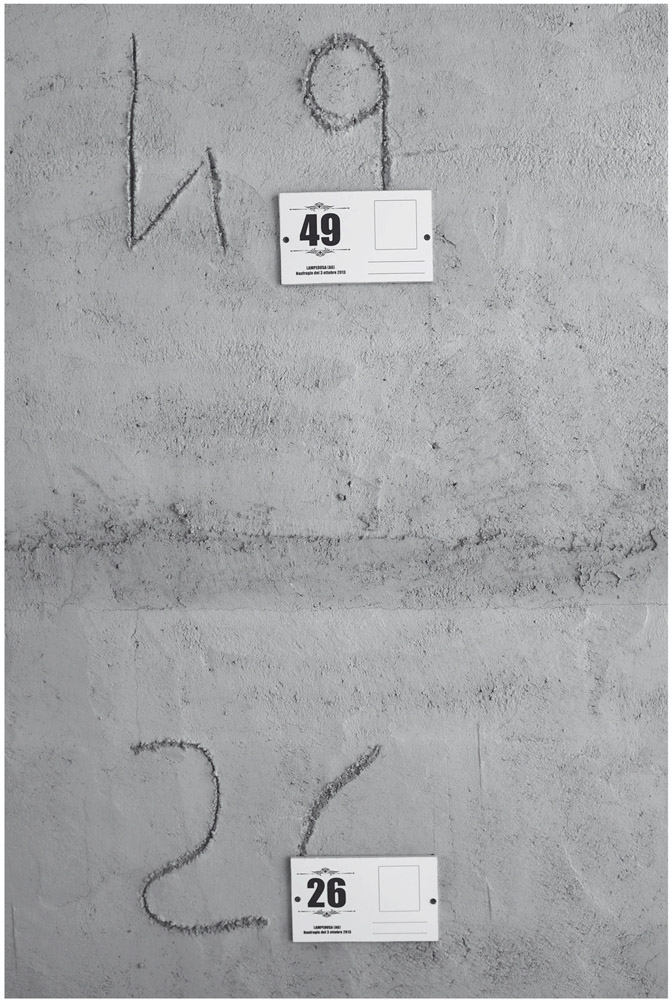 Figure 7. The numbers 49 and 26 are carved into cement one below another and a label with the corresponding number is covering each. The labels have a blank rectangle and lines on them, missing a photo and name.