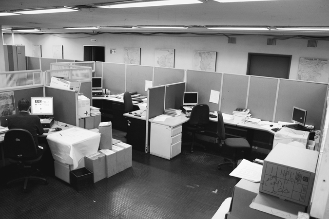 Figure 5.1B. An office with several cubicles, in one of which sits a man at a desk, working at his computer.