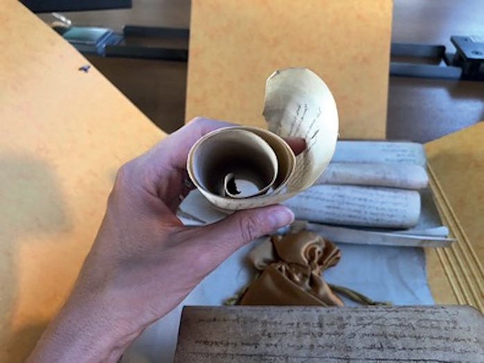 Figure 5. A medieval parchment roll held in a person’s hand, looking through the open end on one side of the rolled-up document.