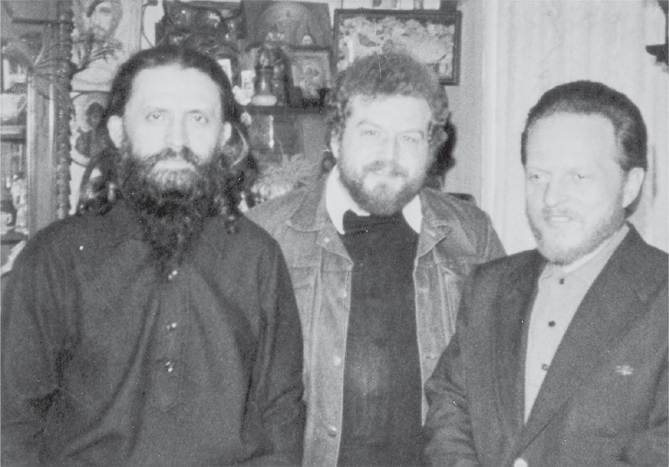 Three bearded men with full heads of hair. The one on the left looks intense, the other two are smiling.