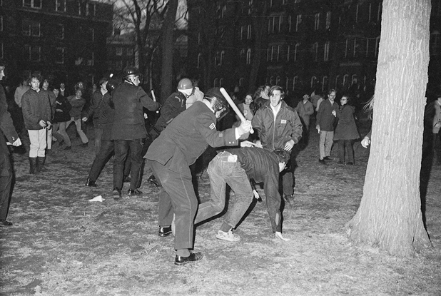 Figure 22. Harvard Yard is filled with police and students. One policeman has his baton raised about to hit a student who has slipped as another student yells at the policeman. Other students look on, stunned as police charge them.