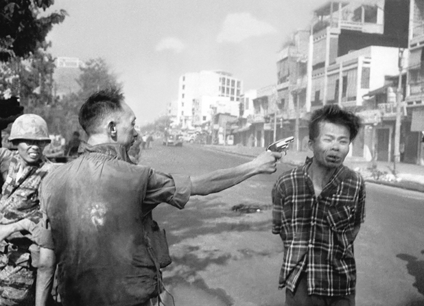 Figure 26. A man in military garb extends his hand with a piston to within inches of a young Vietnamese man in civilian clothes, clearly firing into his head. The younger man has one eye closed, his hands tied behind his back, his bloody lips form a sharp grimace.