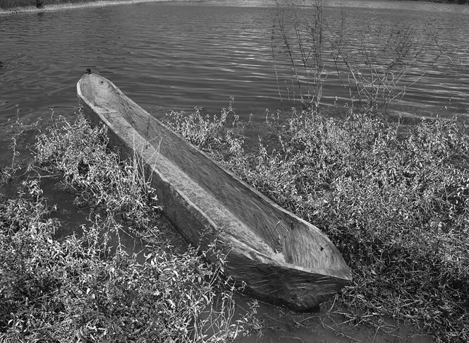 A traditional wooden Mexican cayuco sits in shallow water.