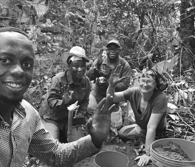 Kate Jackson and three colleagues smile and wave as they build a pitfall trap array.