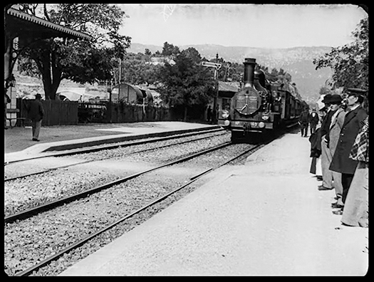 Figure I.1. A still photograph of a steam train pulling into a station with a group of people standing on the platform. The composition of the frame makes it look as if the train might burst through the screen if it keeps going.