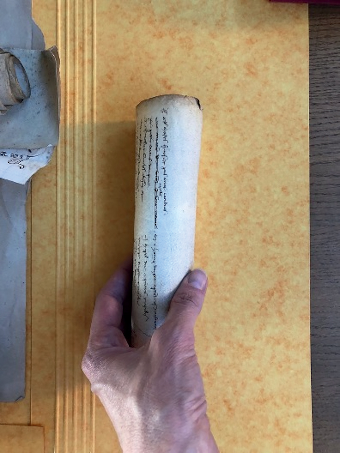 Figure 4. A medieval parchment roll, rolled up, held lengthwise in a person’s hand.