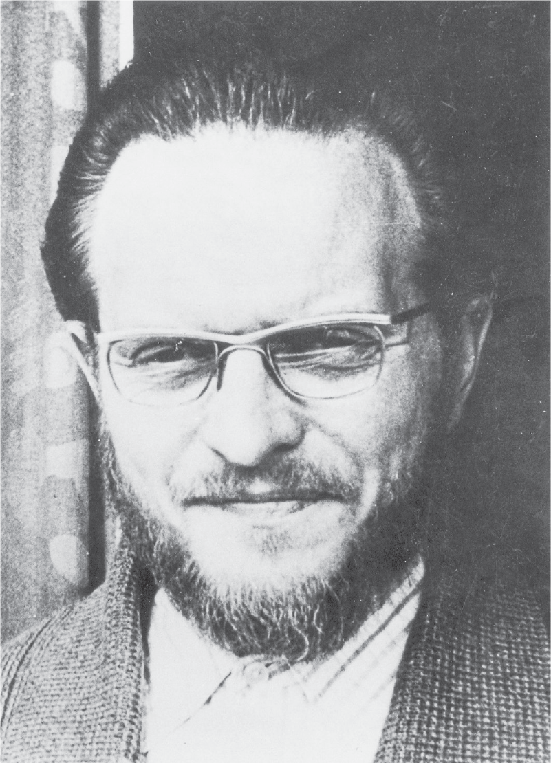 Headshot of a bearded man in glasses squinting in the light.