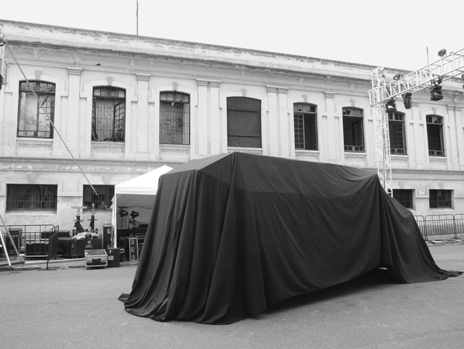 Figure E.1. A large, long building on a city street, in front of which is a structure draped in a black cover.