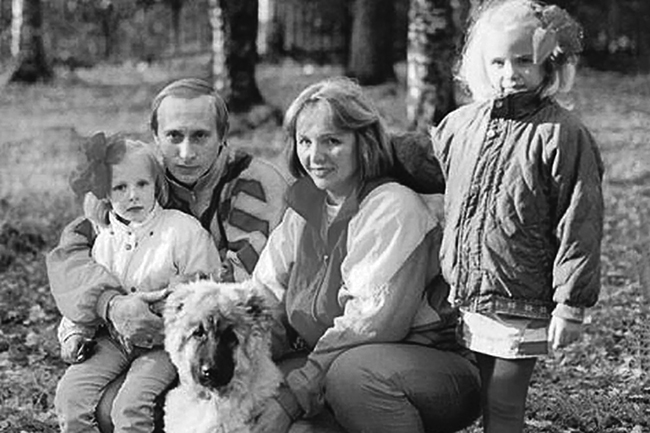 Vladimir Putin and his wife Liudmila smiling in a photograph with their two daughters and their dog.