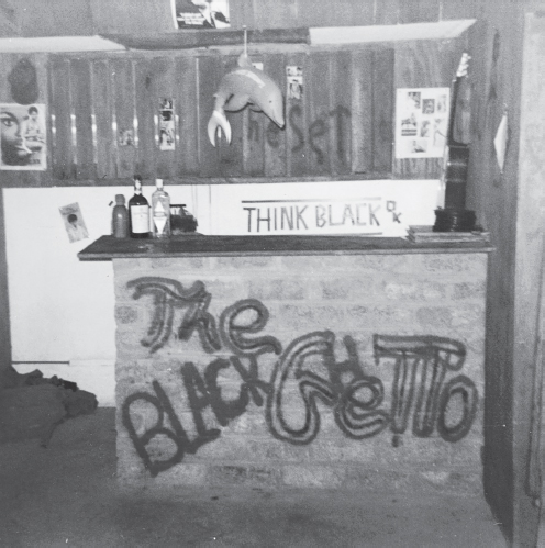 A small bar counter with “The Black Ghetto” spray-painted on the front inside a onetime African American–only establishment in South Vietnam. “Think Black” is spelled out on the wall behind the bar in pieces of black tape.