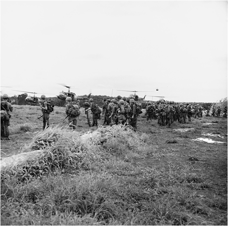 Figure 6. Dozens of soldiers are lined up to board helicopters in a grassy field.