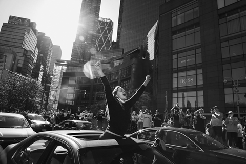 Figure 19. A woman stands in a car’s open sunroof and raises her arms in triumph.