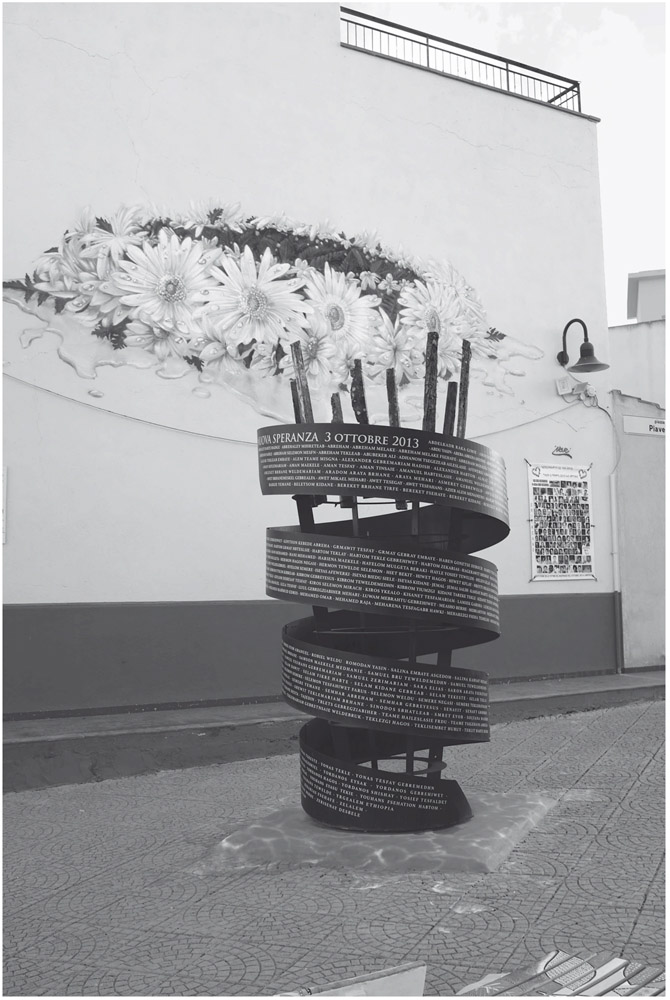 Figure 11. A monument in front of a mural and a poster reads a long list of names. The mural is of a drenched wreath of flowers.