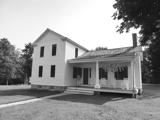 Figure 12 The L-shaped house is now covered with white-painted clapboards instead of wood shingles, and the enclosed porch is opened up, with two elegant single-story Doric columns. The second story behind the porch has been removed.