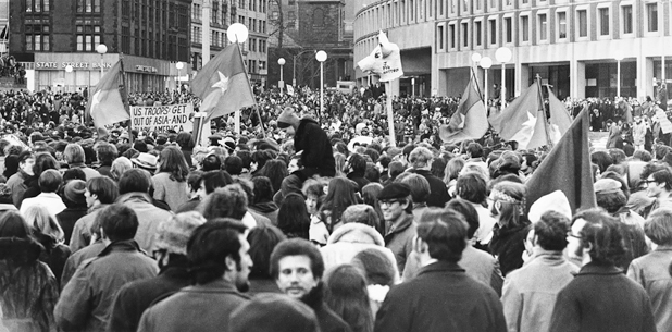 Figure 34. Thousands of protestors marching in downtown Boston carrying NLF flags, a papier-mâché pigs head, and a sign that says, “US Troops Get Out of Asia.”