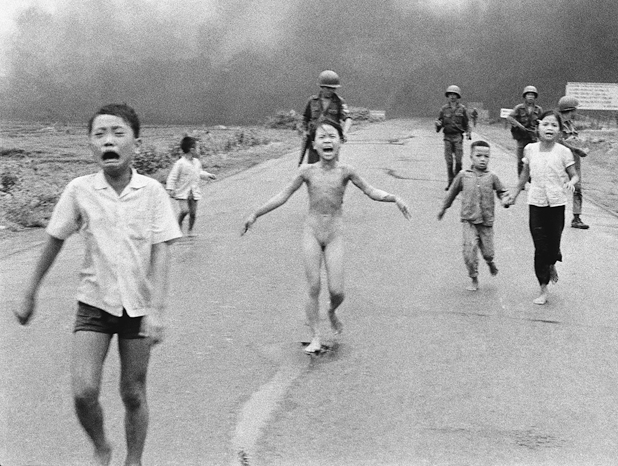 Figure 27. Five Vietnamese children are running. One, a young girl, is screaming, totally naked. In front of her is a young boy screaming. Behind a boy has turned to look back at the smoke and flames they are fleeing from. Behind them are four South Vietnamese soldiers, seemingly undisturbed.