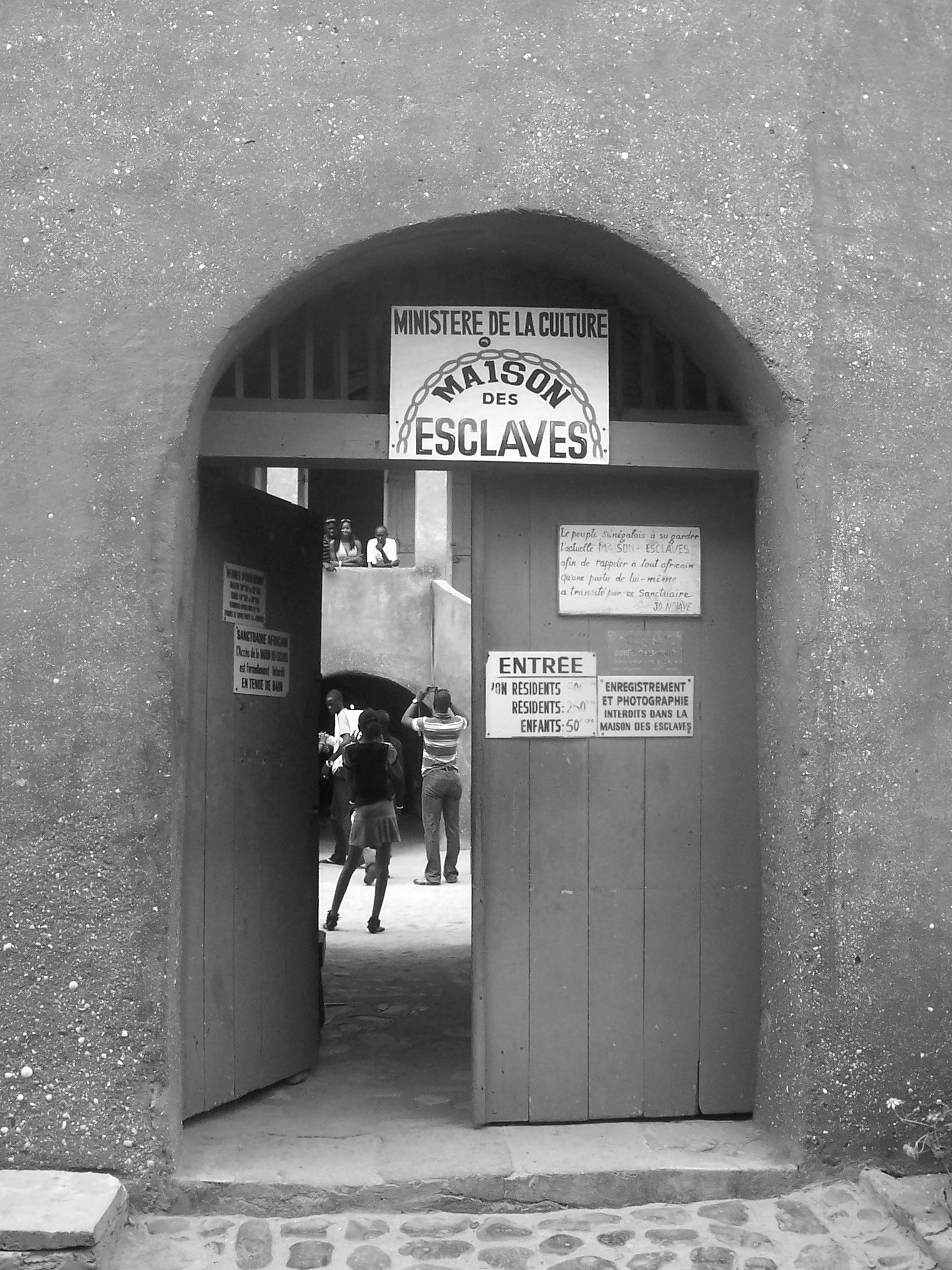The entrance of Maison des Esclaves. The door is open and tourists are visible inside the building.