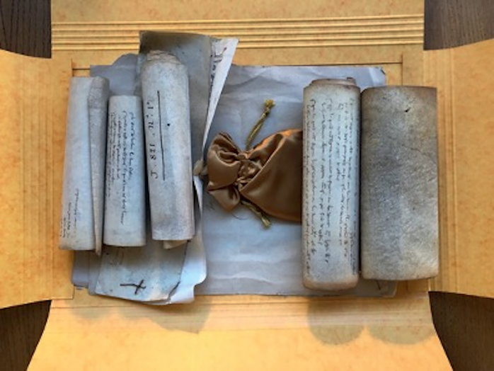 Figure 3. An open archival folder of five medieval parchment rolls with a seal in a seal bag at the center.
