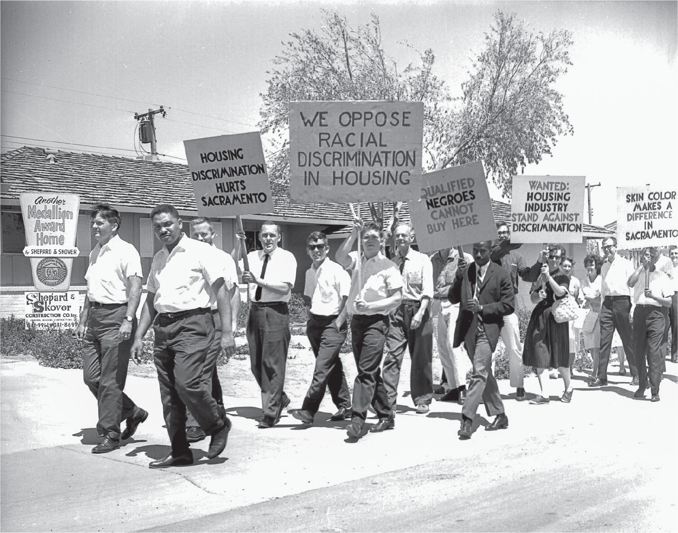 Figure 3.2. Members of the SCFH marching along a street holding signs protesting housing discrimination.
