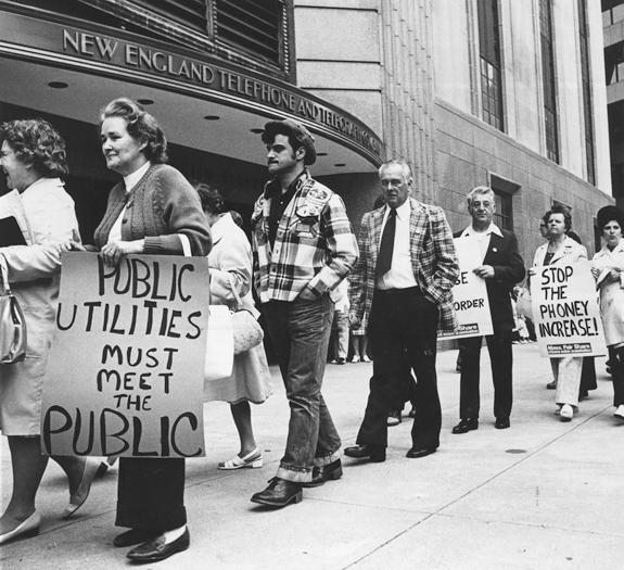 Figure 52. A picket line outside of the New England Telephone and Telegraph Company. The protestors are middle aged and working class with signs that say, “Public Utilities Must Meet the Public” and “Stop the Phoney [sic] Increase, Mass Fair Share.”