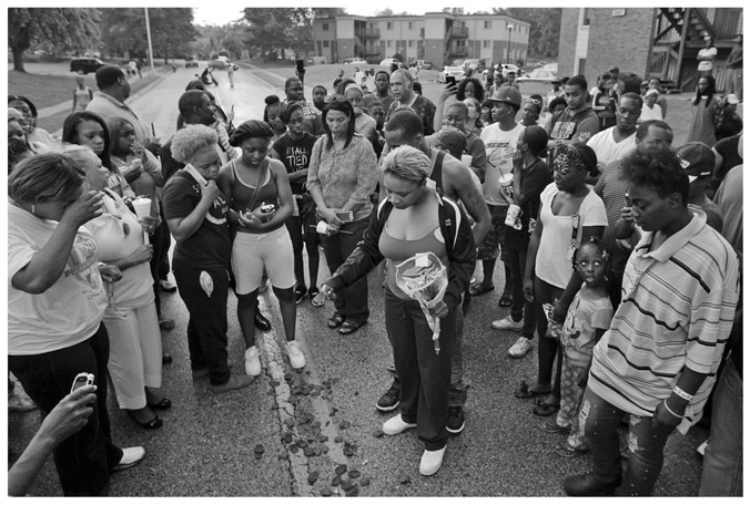 FIGURE A.2 “Lezley McSpadden, center, drops rose petals on the blood stains from her 18-year-old son Michael Brown who was shot and killed by police in the middle of the street in Ferguson, Mo., near St. Louis on Saturday, Aug. 9, 2014.”Associated Press/St. Louis Post-Dispatch. Photo by Huy Mach.
