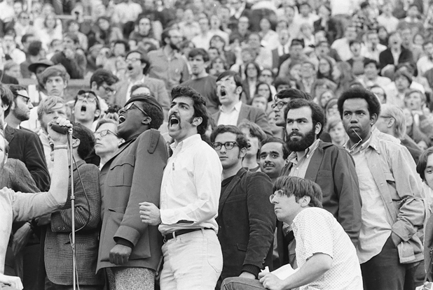 Figure 24. Students are all standing. A group in the lower seats, cluster by a microphone. Everyone yells “yes” to ratify the demands. Near the group, I stand, with my black beard, looking intense, observing the crowd and its unity.