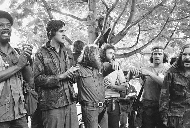Figure 45. A group of young men, standing under a tree, either singing or chanting. They are wearing parts of old uniforms; most are bearded. In the background one has climbed up into the tree.