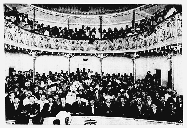 Figure 1.2. A large audience in a performance hall, including women with haik visible in both stage-level seats and a balcony level.
