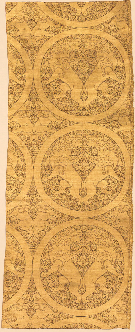 Figure 5. A strip of fabric of gold thread woven on a brown silk foliate ground showing confronted winged lions in roundels. Between the roundels are confronted griffins.
