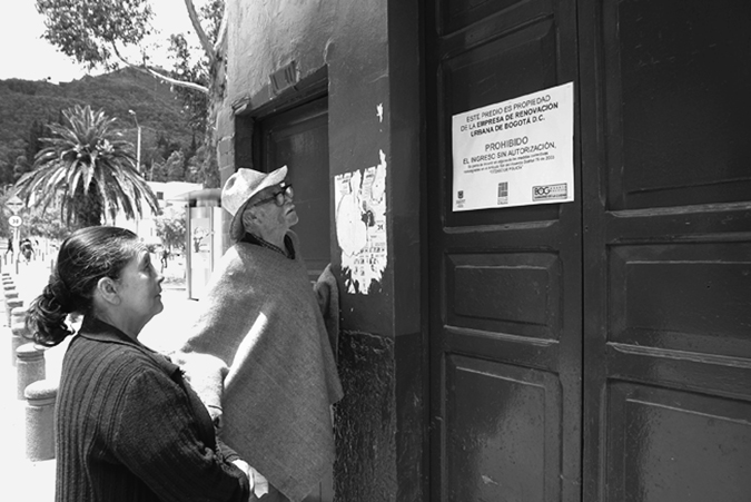 Figure 3.2. A man and a woman stand in front of the door to a building, reading a sign posted on it.