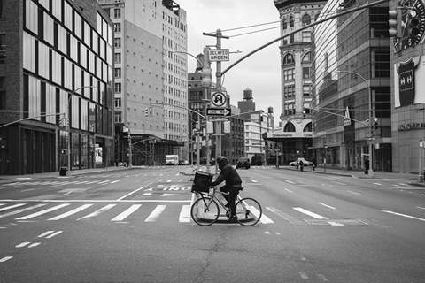 Figure 24. A city street is empty except for a food delivery worker on a bicycle.
