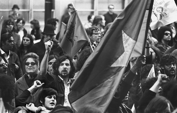 Figure 31. A crowd of young protestors march with the flag of the National Liberation Front in the center, fists raised.