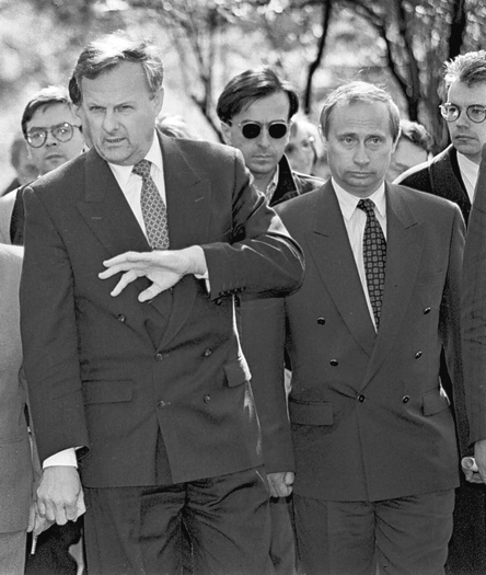 Anatoly Sobchak walking with Vladimir Putin and gesturing with his hand in the early 1990s.
